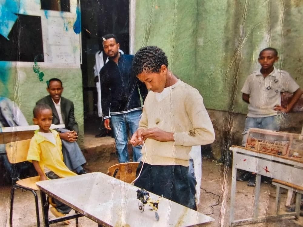 Abel Birhanu as a 4th grader at a school Parents' Day, showing a small motorcycle he built